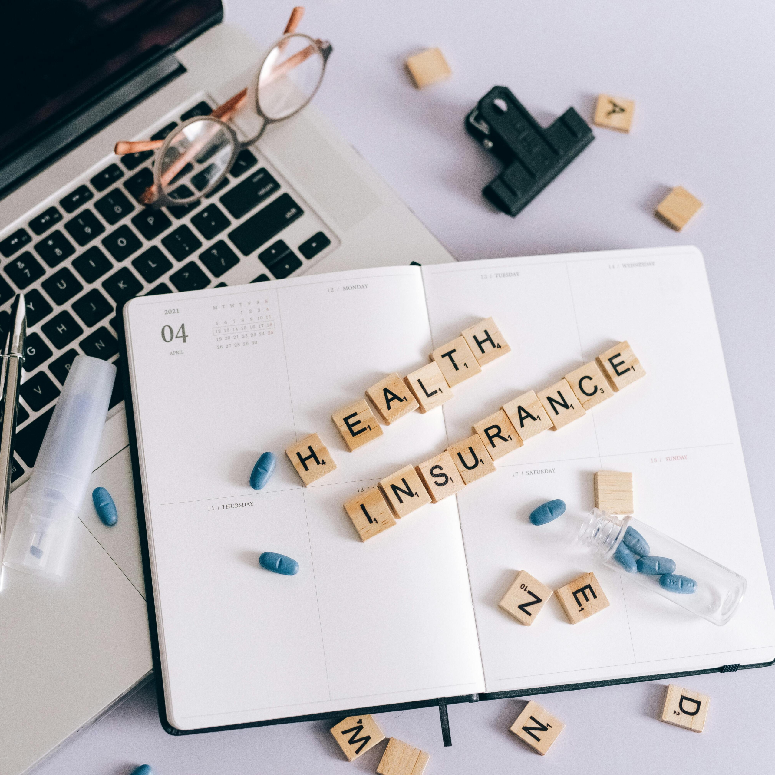Laptop and wooden block spelling out Health Insurance