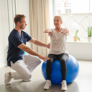 Person sitting on an exercise ball next to clinician
